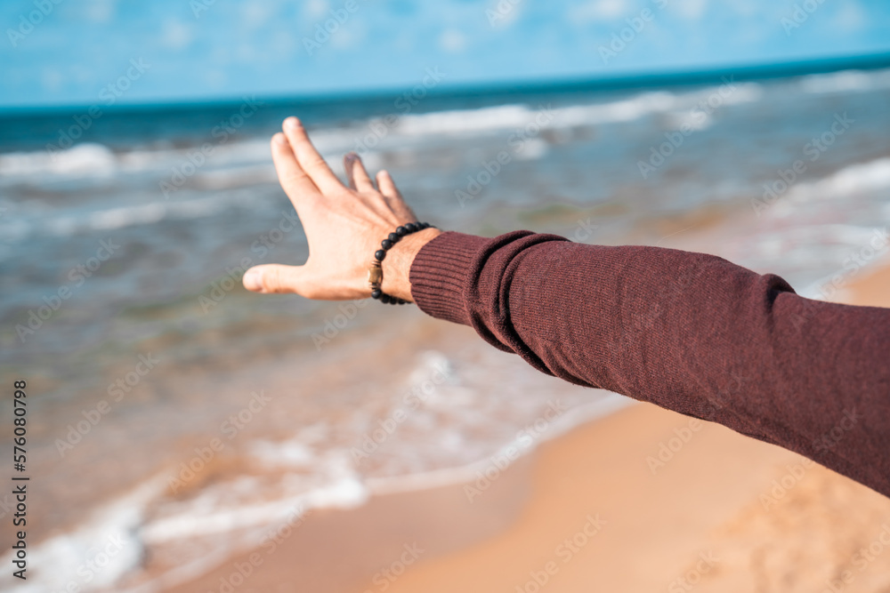 Human hand on the background of waves. Man on the sea or ocean. Atmospheric photo from a trip or vacation. Nice day. Walk along the coast. Human hand on the background of waves. Man on the sea or ocean. Atmospheric photo from a trip or vacation. Nice day. Walk along the coast.