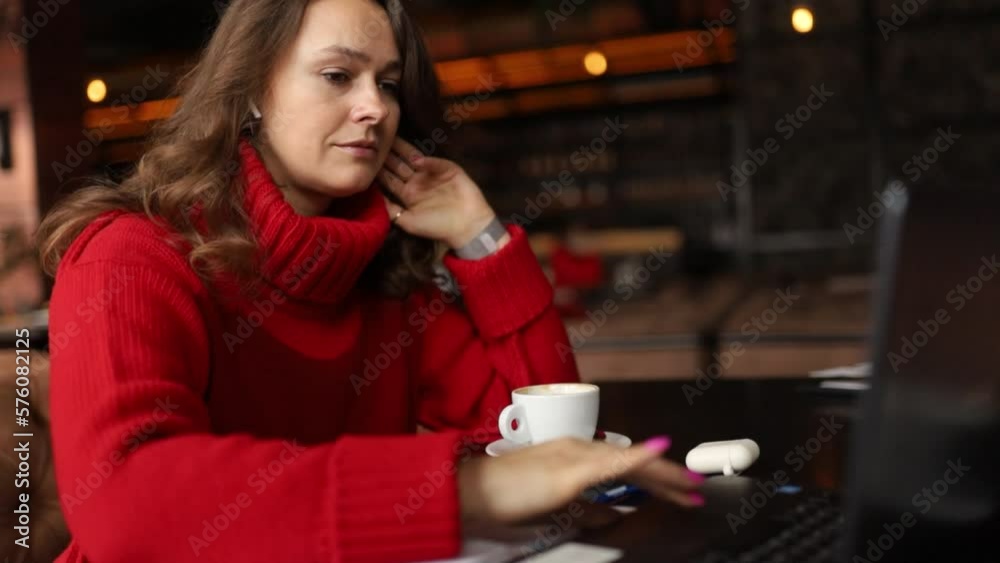 woman in a red sweater works on the Internet online with a cup of coffee in coworking woman in a red sweater works on the Internet online with a cup of coffee in coworking