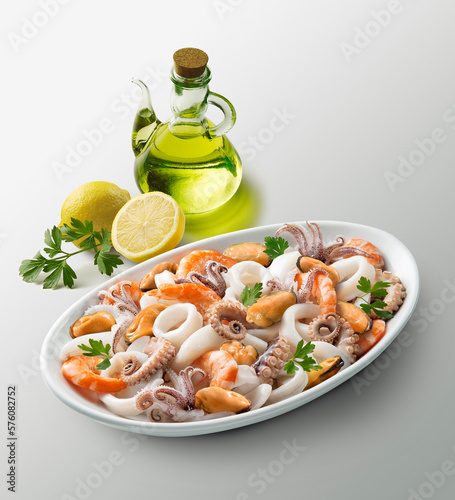 Oval white plate with seafood salad lemons parsley and cruet with oil