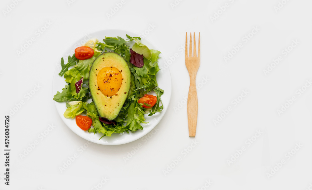 Baked egg with avocado and lettuce leaves on white plate. Fodmap diet concept. Baked egg with avocado and lettuce leaves on white plate. Fodmap diet concept.