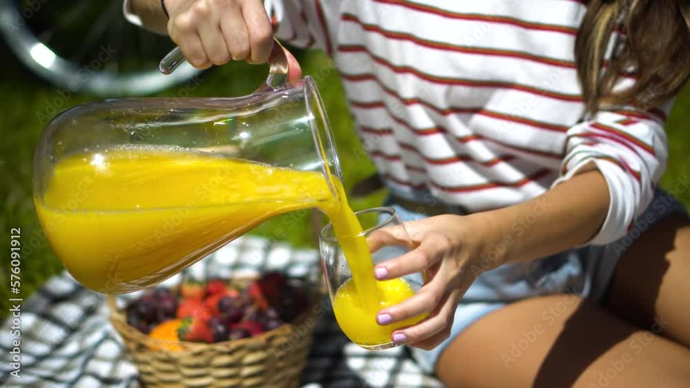 Mujer sirviendole jugo de china con jarra a su novio en un picnic de los años 80's
