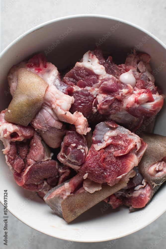 Fresh raw goat meat in a white bowl, chopped goat meat being prepared for cooking Fresh raw goat meat in a white bowl, chopped goat meat being prepared for cooking
