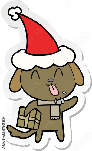 cute sticker cartoon of a dog with christmas present wearing santa hat