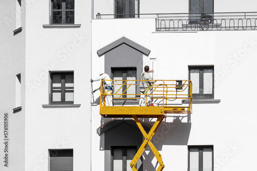 Two painters painting the facade of the building with paint rollers © Pavel Iarunichev