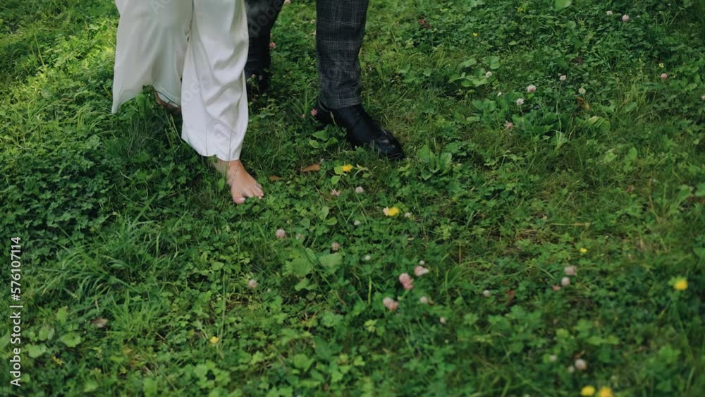 A man and a woman are walking on the grass in nature. Shooting the feet of lovers A man and a woman are walking on the grass in nature. Shooting the feet of lovers