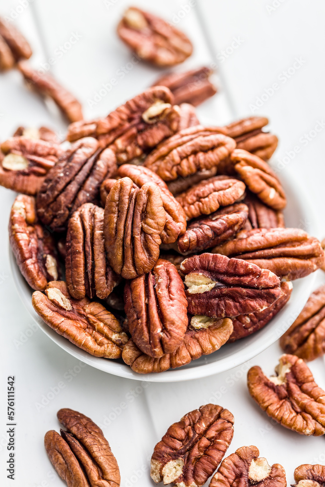 Peeled pecan nuts in bowl on white table. Peeled pecan nuts in bowl on white table.