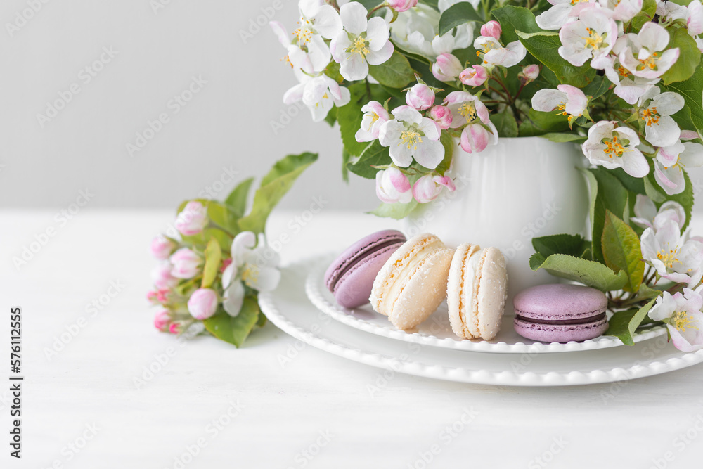 Beautiful composition with delicious French macarons and spring flowers in a white cup. Sweet dessert, early spring white and pink flowers, wedding decor, bride morning Beautiful composition with delicious French macarons and spring flowers in a white cup. Sweet dessert, early spring white and pink flowers, wedding decor, bride morning