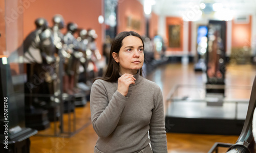Female museum visitor examining with interest ancient iron armor displayed on exhibition .. photo