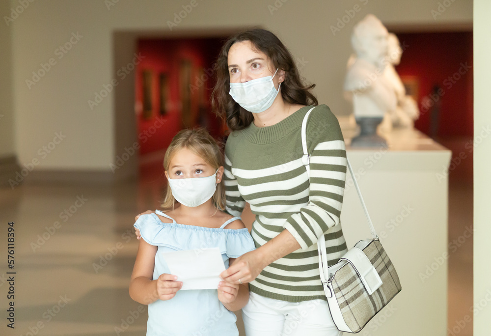 Mom and her daughter in protective masks on a tour of the museum