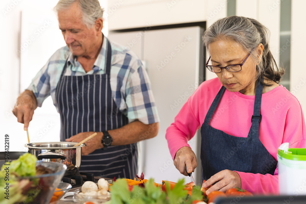 Happy senior diverse couple cooking dinner in kitchen
