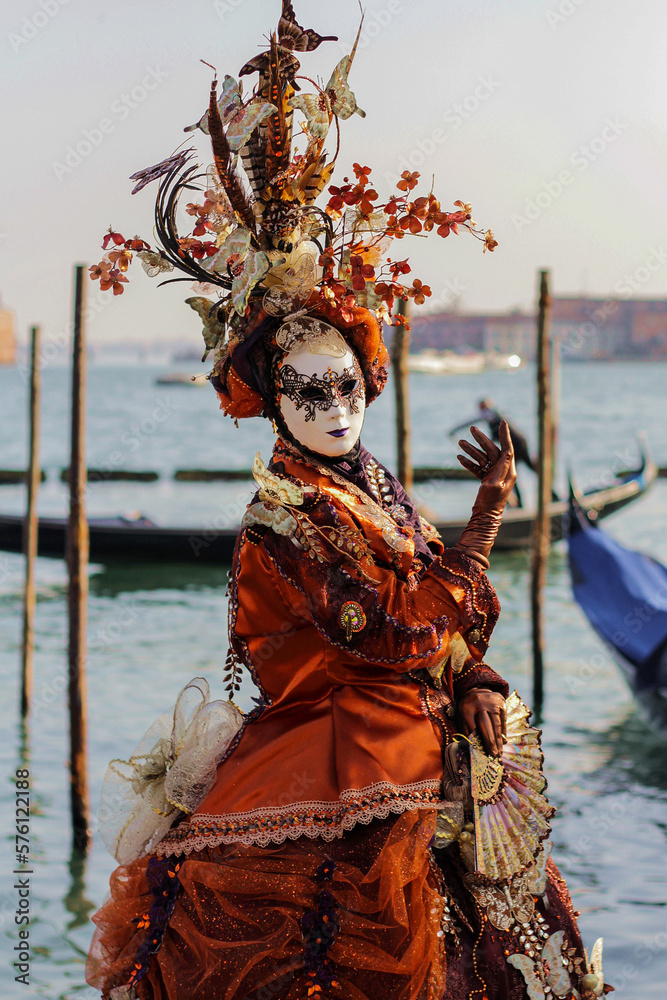 Venetian carnival mask in orange costume, traditional carnival in Venice, Italy, person in costume.