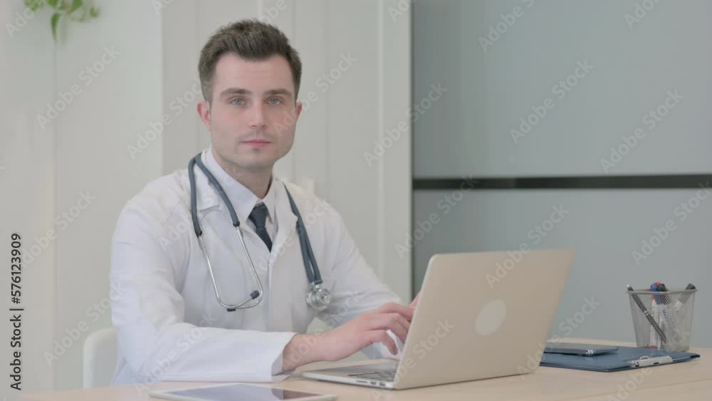 Young Doctor Looking at Camera while using Laptop Young Doctor Looking at Camera while using Laptop