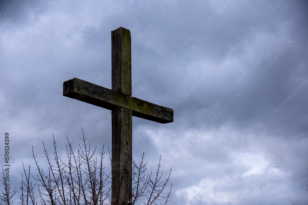 Christian wooden cross against background with dramatic dark clouds and sky