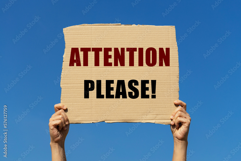 Attention please text on box paper held by 2 hands with isolated blue sky background. This message board can be used as business concept to inform everyone pay an attention. Attention please text on box paper held by 2 hands with isolated blue sky background. This message board can be used as business concept to inform everyone pay an attention.