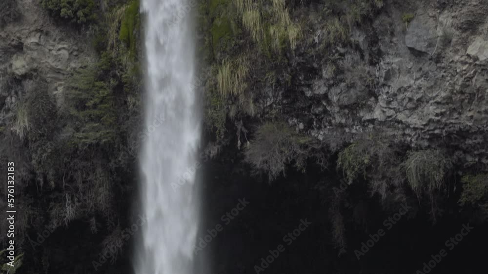 waterfall falling into dark cave entrance, early evening waterfall falling into dark cave entrance, early evening