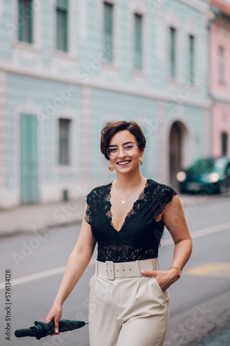 Woman wearing beige pants and a black lace top walking in the city street