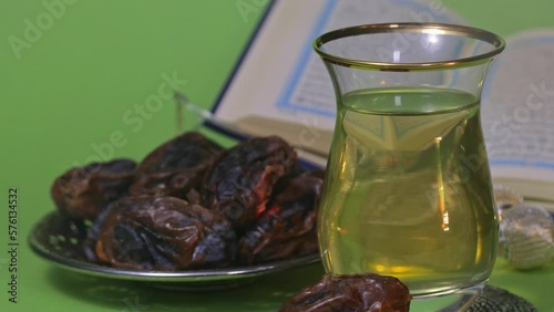 Glass of Turkish tea and dates in a silver plate on a green screen photo