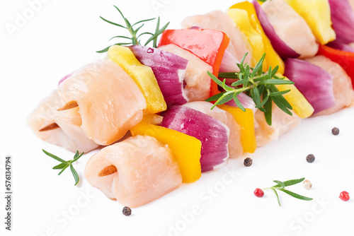 Skewers with pieces of raw meat, red, yellow and green pepper.Raw pieces of chicken skewers with pepper onion and pineapple on a white background.Uncooked mixed meat skewer with peppers.Top view. photo