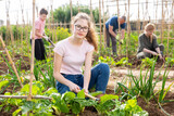 Portrait of cute teen girl helping her family in vegetable garden on sunny spring day.