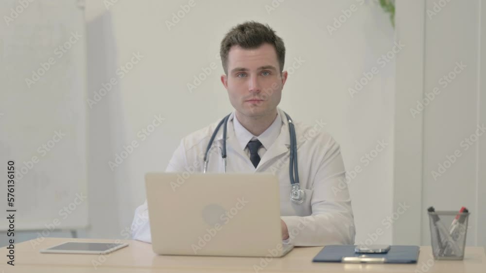Young Doctor Looking at Camera while using Laptop Young Doctor Looking at Camera while using Laptop