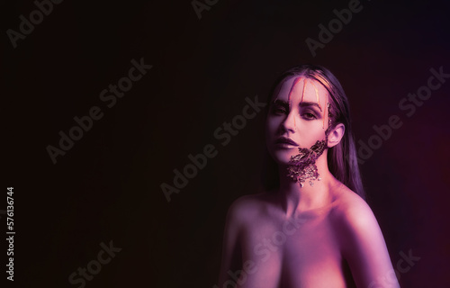 Toned portrait of naked young woman with golden paint on her face against black background. Banner for design
