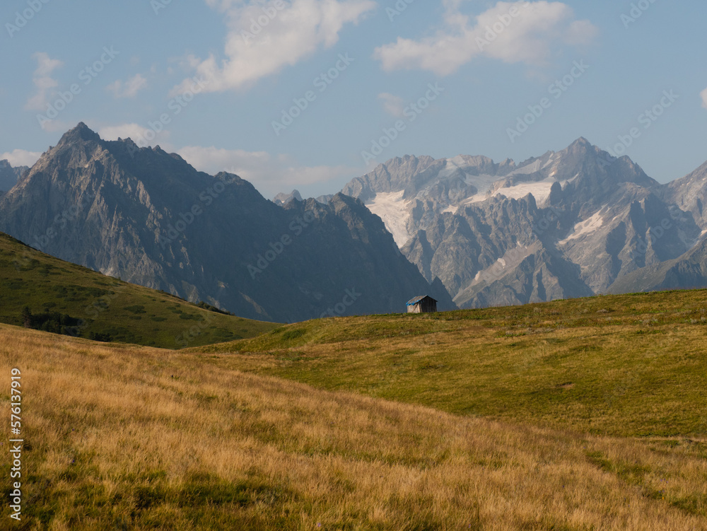 Caucasus mountains with hut in the foreground.