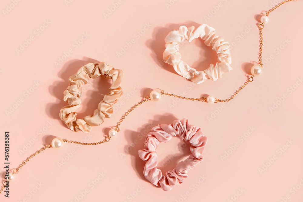 Naklejka premium Silk scrunchies and necklace on pink background