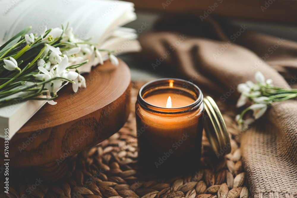 Burning candle and beautiful flowers on wooden table indoors - obrazy, fototapety, plakaty 
