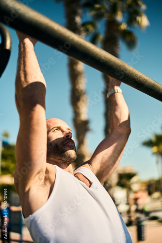 young guy exercising with calisthenics workout in an outdoor gym