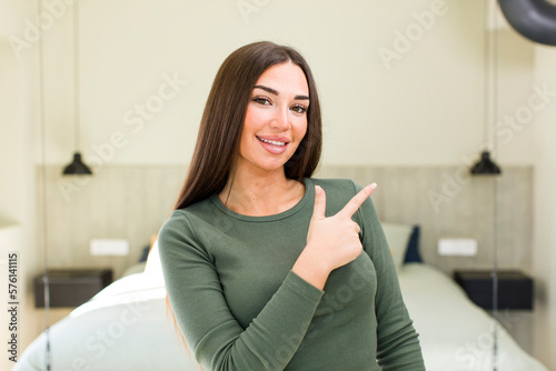 young adult pretty woman looking excited and surprised pointing to the side and upwards to copy space
