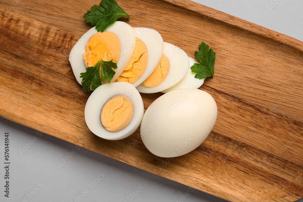 Board with slices of delicious boiled eggs and parsley on grey background Board with slices of delicious boiled eggs and parsley on grey background