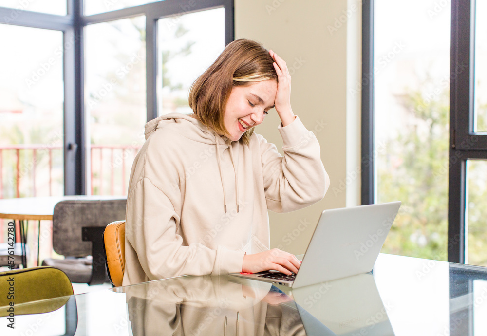 pretty caucasian woman laughing and slapping forehead like saying d’oh! I forgot or that was a stupid mistake. home interior concept pretty caucasian woman laughing and slapping forehead like saying d’oh! I forgot or that was a stupid mistake. home interior concept