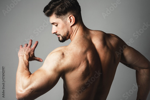 Muscle handsome young man posing over gray background. Perfect body and skin. Studio shot.