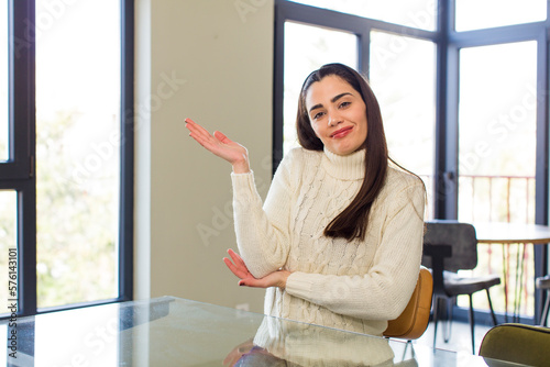 pretty caucasian woman smiling proudly and confidently, feeling happy and satisfied and showing a concept on copy space