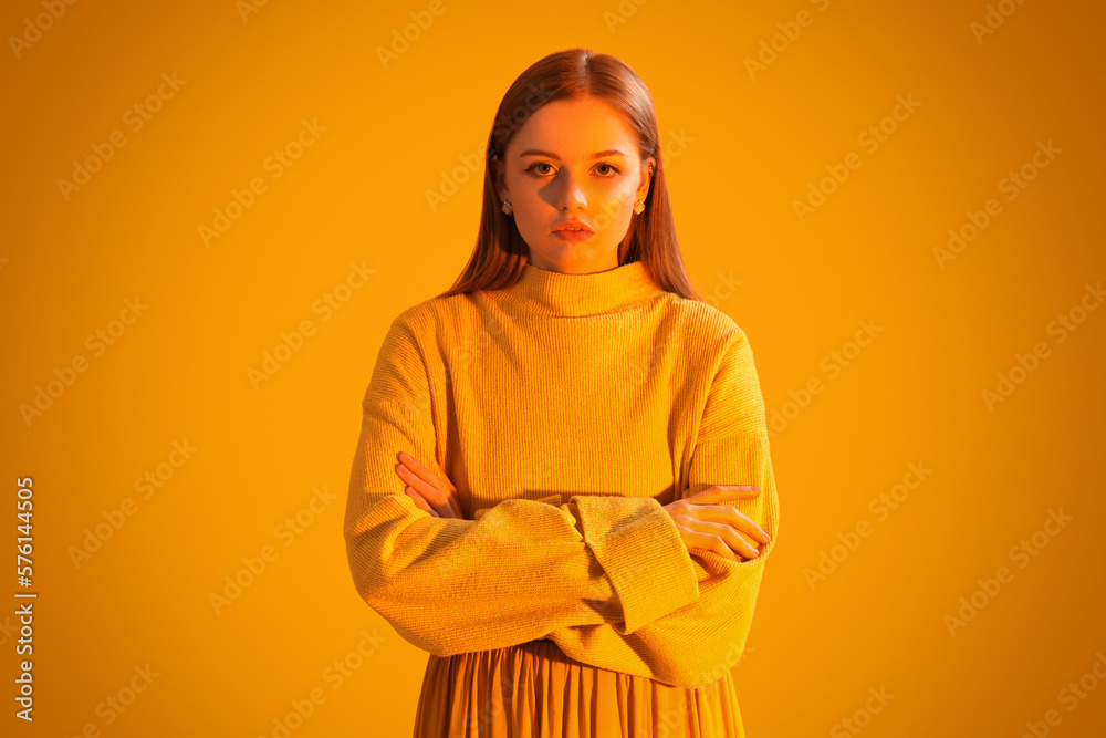 Fototapeta premium Fashionable young woman in knitted sweater on orange background