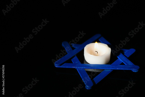 Burning candle with David star on dark background. International Holocaust Remembrance Day photo