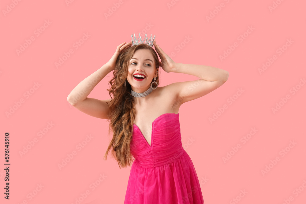 Young woman in crown and bright prom dress on pink background Young woman in crown and bright prom dress on pink background