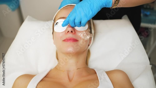 Cosmetologist covering woman's eyes with protective glasses before thermolifting. High quality 4k footage photo