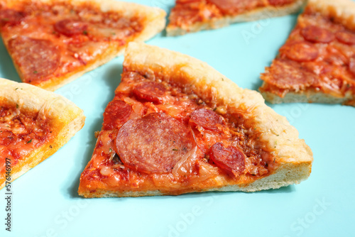Slices of delicious pepperoni pizza on turquoise background, closeup