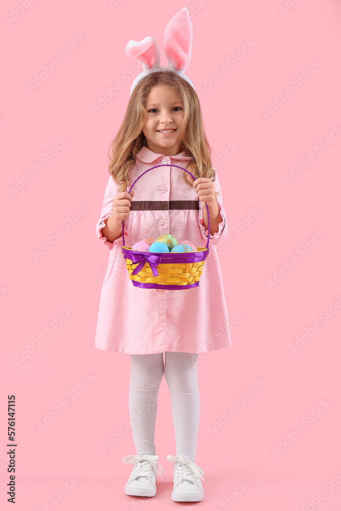 Cute little girl in bunny ears with basket of Easter eggs on pink background Cute little girl in bunny ears with basket of Easter eggs on pink background