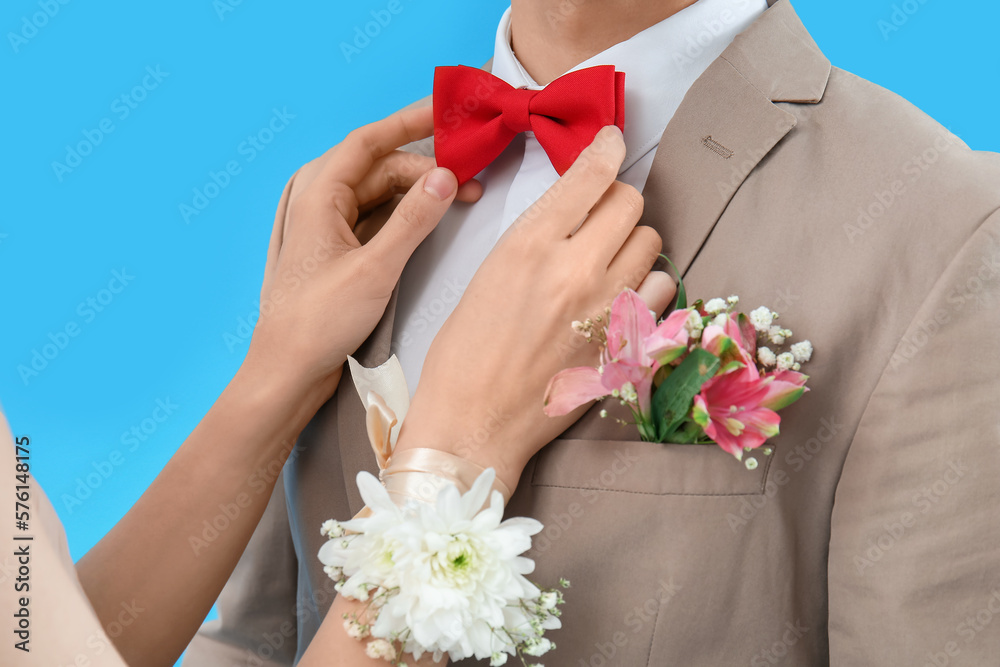 Young girl fixing bowtie of her prom date on blue background, closeup Young girl fixing bowtie of her prom date on blue background, closeup
