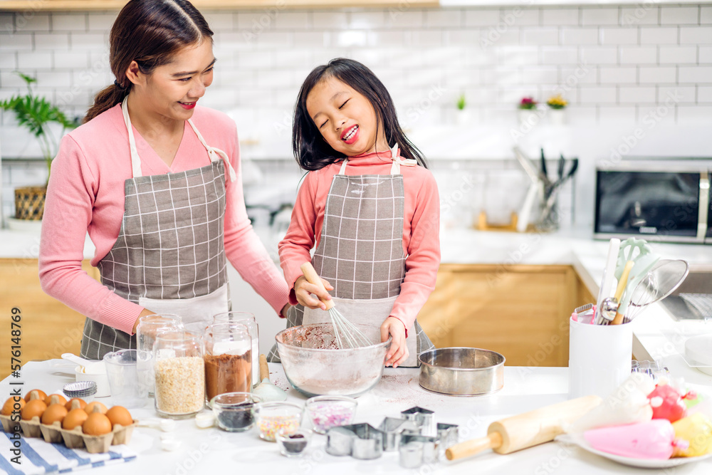 Portrait of enjoy happy love asian family mother and little toddler asian girl daughter child having fun cooking together with dough for homemade bake cookie and cake ingredient on table in kitchen Portrait of enjoy happy love asian family mother and little toddler asian girl daughter child having fun cooking together with dough for homemade bake cookie and cake ingredient on table in kitchen