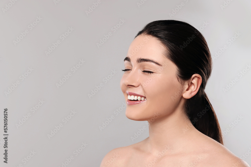 Portrait of attractive young woman with smooth skin on grey background. Space for text Portrait of attractive young woman with smooth skin on grey background. Space for text