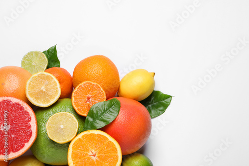 Different citrus fruits with fresh leaves on white background  top view. Space for text