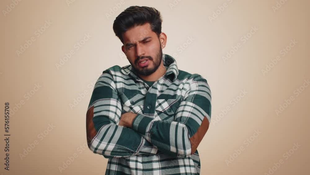 Dislike. Upset unhappy indian man in shirt showing thumbs down sign gesture, expressing discontent, disapproval, dissatisfied, dislike. Handsome young guy. Indoor studio shot on beige background Dislike. Upset unhappy indian man in shirt showing thumbs down sign gesture, expressing discontent, disapproval, dissatisfied, dislike. Handsome young guy. Indoor studio shot on beige background