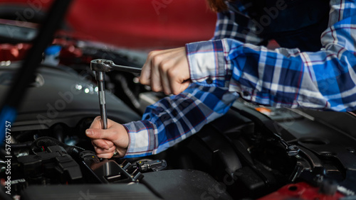 Female auto mechanic unscrewing a nut to replace a car spark plug.