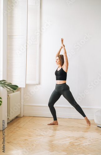 Young slim woman in sportwear doing fitness exercises, girl dancing at bright studio