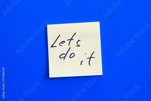 Lets do it inscription on a yellow piece of paper on a blue background