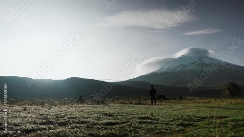 Camper admiring a large snow capped volcano surrounded by beautiful nature Ecuador Cotopaxi