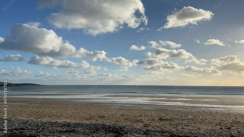 Puff white clouds passing on a blue sunny winter sky while people walking on a sandy beach in time-lapse video. Puff white clouds passing on a blue sunny winter sky while people walking on a sandy beach in time-lapse video.